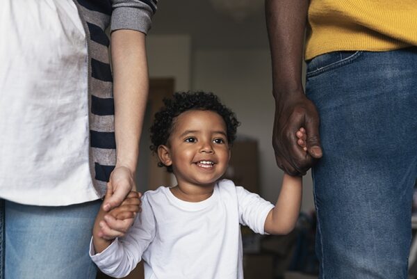 Young kid holding hands with mom and dad